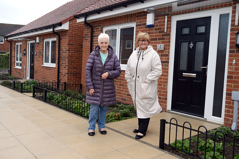 Two people standing outside a house.