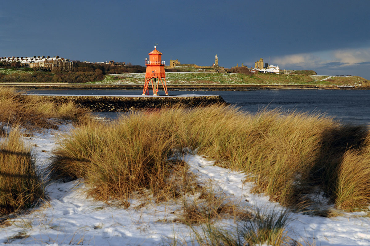 Orange lighthouse on a coastal landscape.