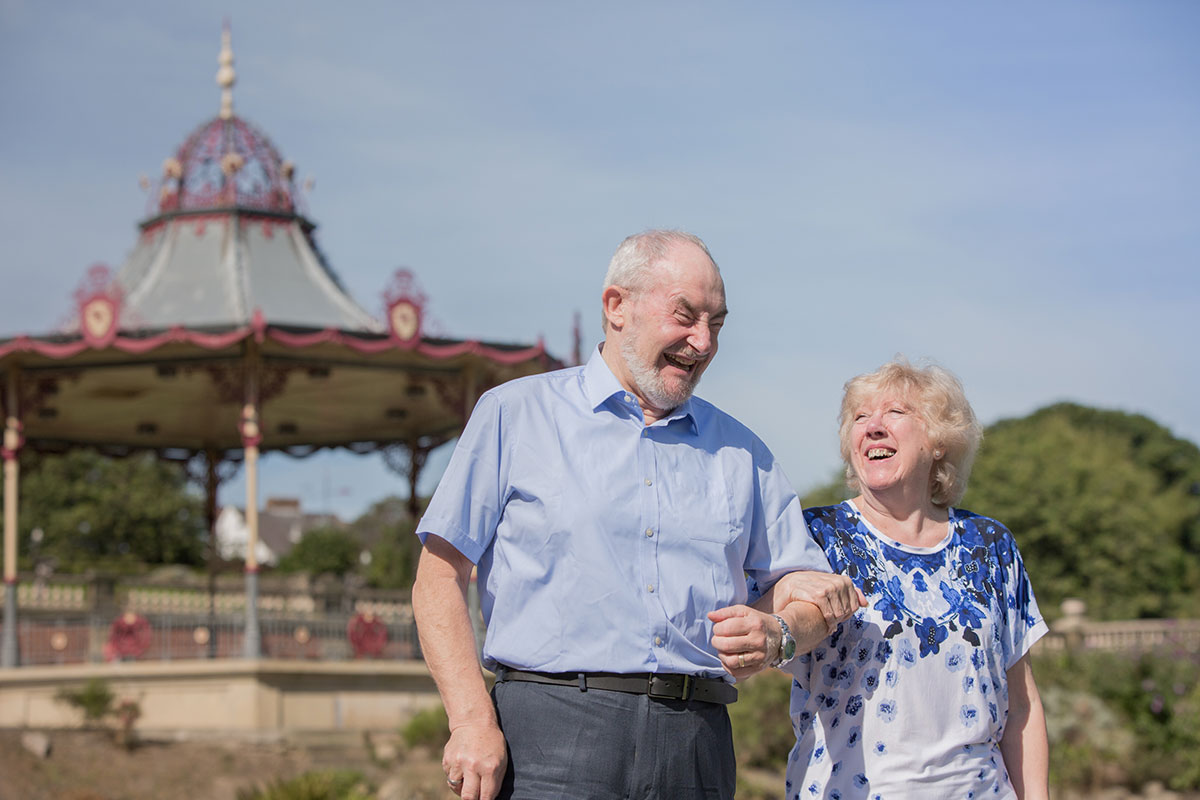 Two people in front of an ornate bandstand.