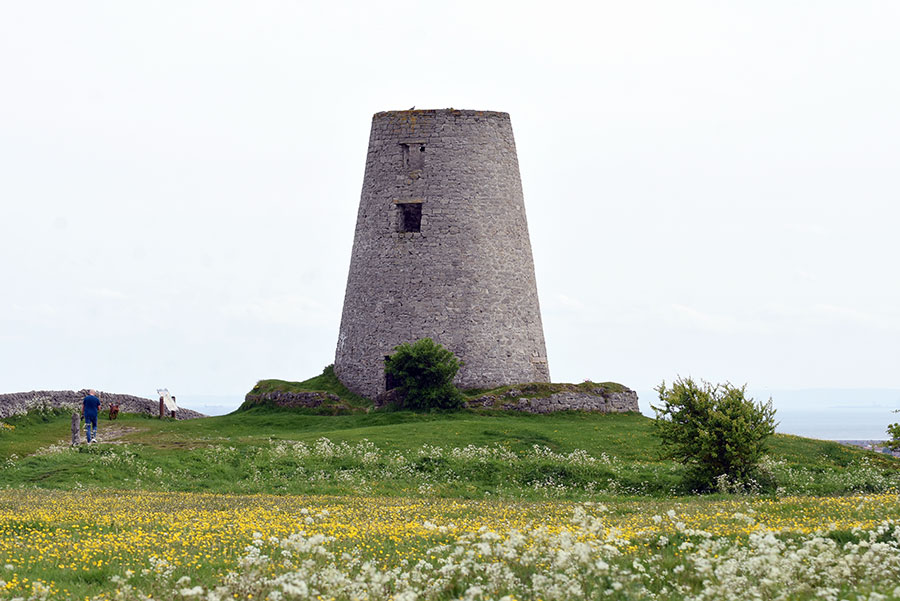 A windmill, without sails, on a hill top.